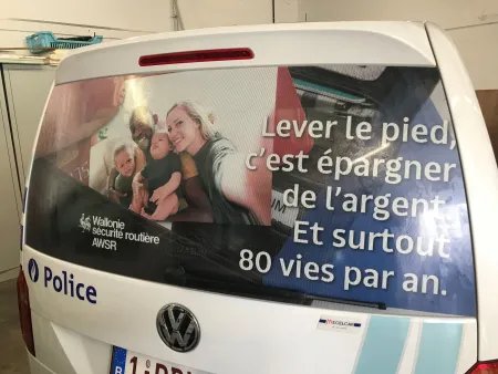 Véhicule de police arborant un message de sécurité routière sur sa vitre arrière Lever le pied, c'est épargner de l'argent. Et surtout 80 vies par an.