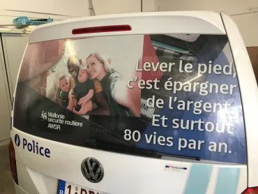 Véhicule de police arborant un message de sécurité routière sur sa vitre arrière Lever le pied, c'est épargner de l'argent. Et surtout 80 vies par an.